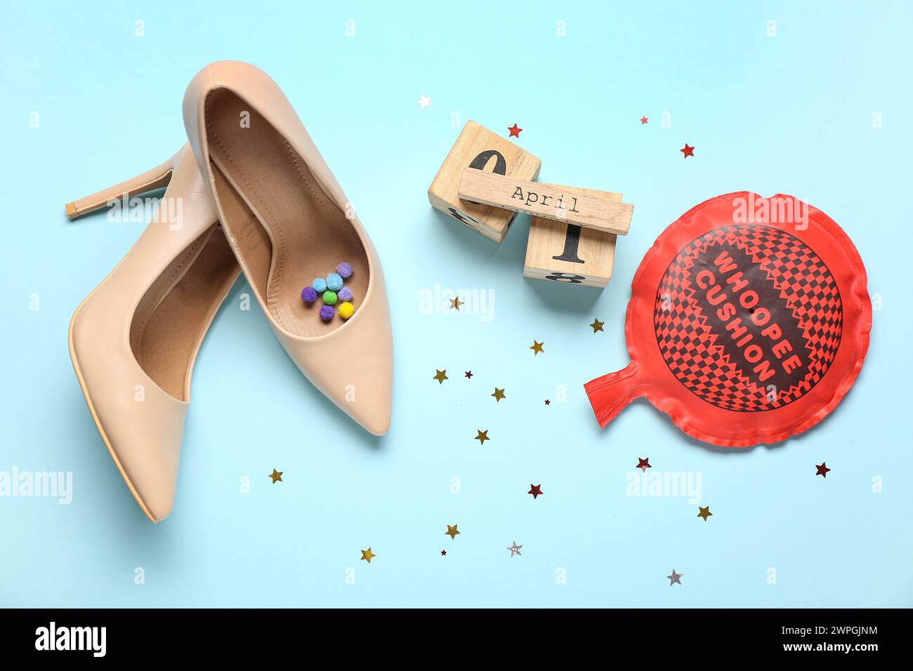 High heel shoes with calendar, whoopee cushion and decor on blue background. April Fools Day Stock Photo