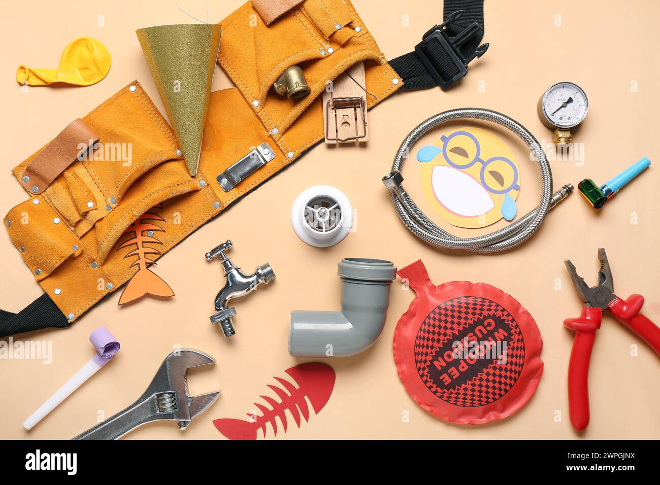 Construction tools with whoopee cushion, mousetrap and party decor on beige background. April Fools Day Stock Photo