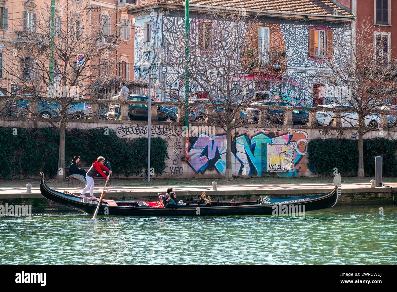 Gondola and gondolier in the Darsena del Naviglio in Milan, Italy. Navigable channel and means of navigation. Tourism and visits to Milan to discover. Stock Photo