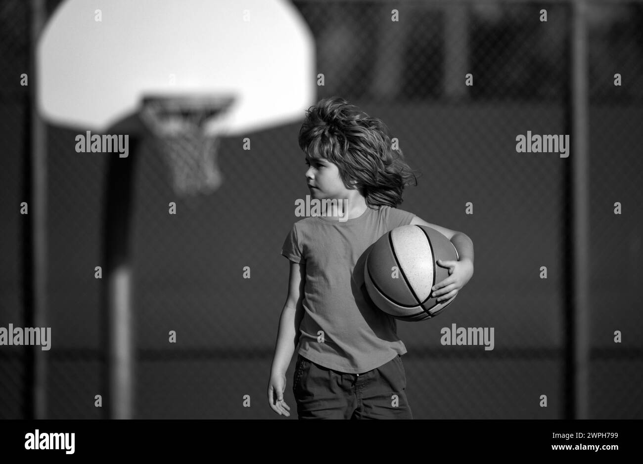 Cute smiling boy plays basketball. Active kids enjoying outdoor game with basket ball. Sport for kids. Stock Photo