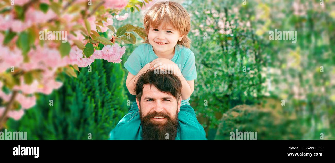 Happy father giving shoulder ride on his shoulders in garden. Banner ...
