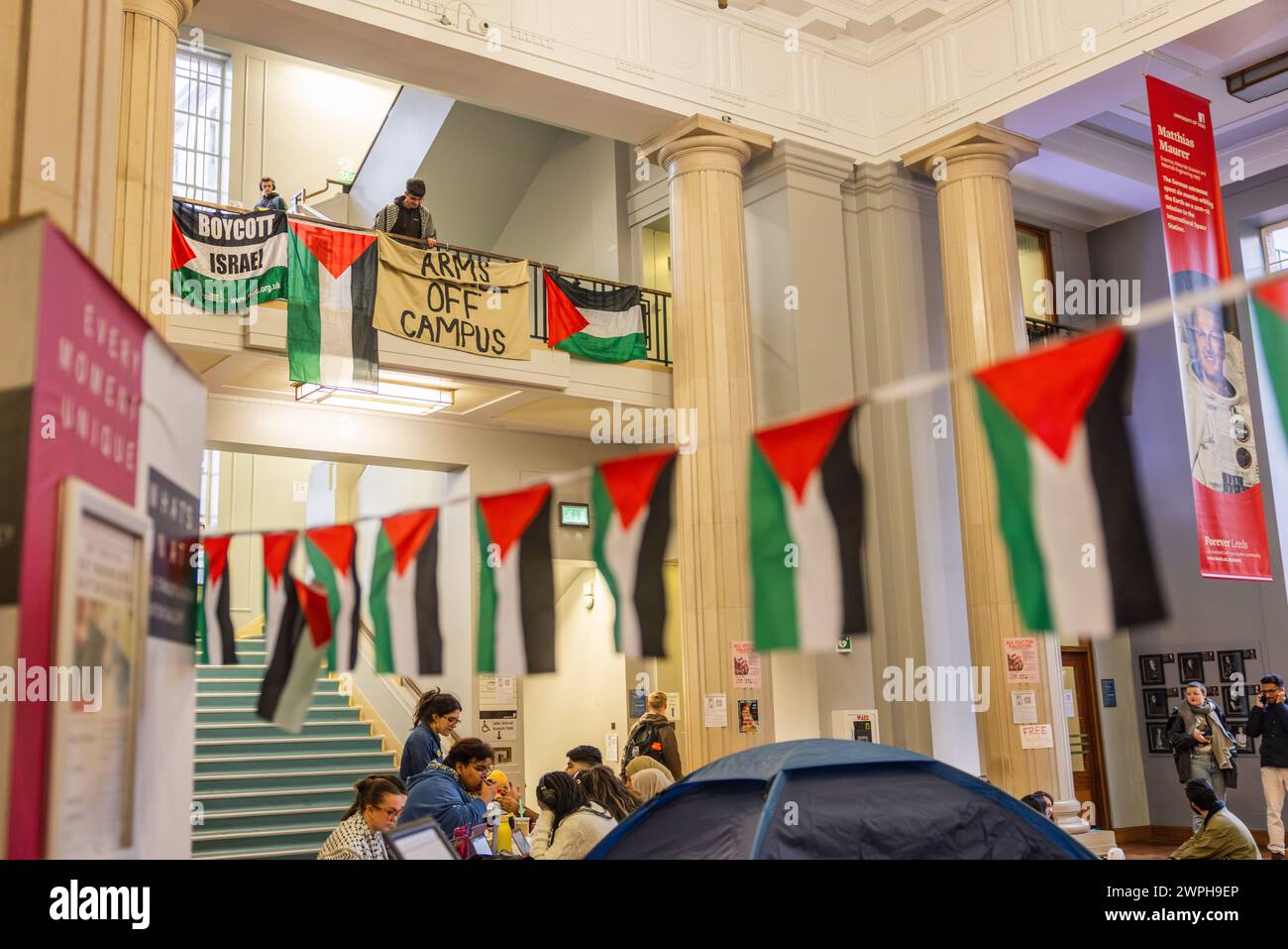 Leeds, UK. 07 MAR, 2024. Pro palestine demonstrator stands with banners on Balcony at University of Leeds. Story: Palestine protestors occupy the Parkinson building at the University of Leeds. The studends demand the suspension of Rabbi Zecharia Deutsch as a Jewish chaplain on campus, the Rabbi had temporarily left UOL to serve in the IDF and subsequently returned to campus and for the university to stop working with BAE/Israeli Universities. Protestors plan to occuply the site for the forseable future. Credit Milo Chandler/Alamy Live News Stock Photo