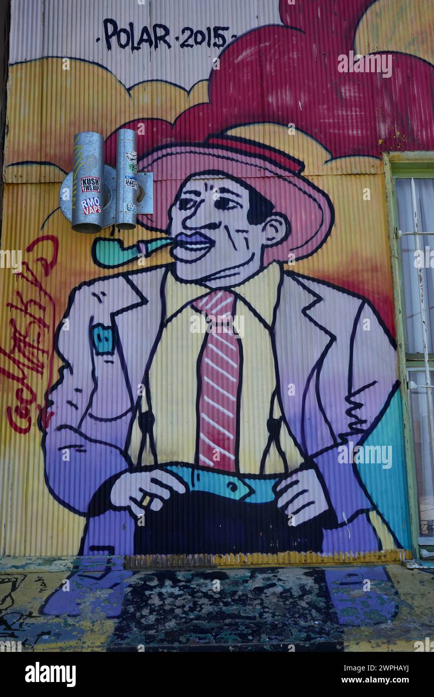Colorful Street art painting of a man smoking a pipe, on a corrugated metal wall. Stock Photo