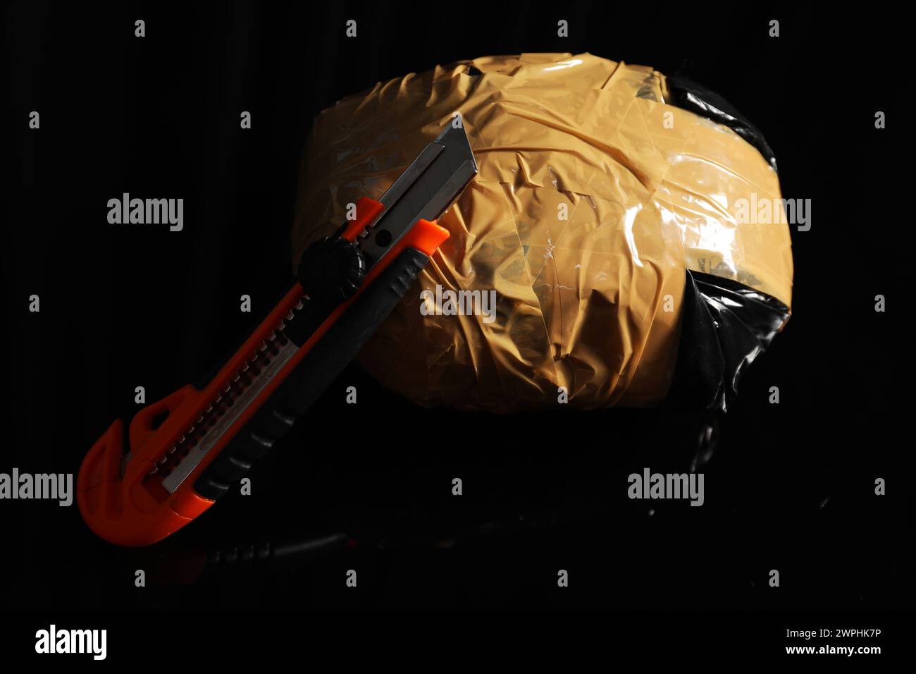 Smuggling, drug trafficking. Package with narcotics and utility knife on black surface Stock Photo