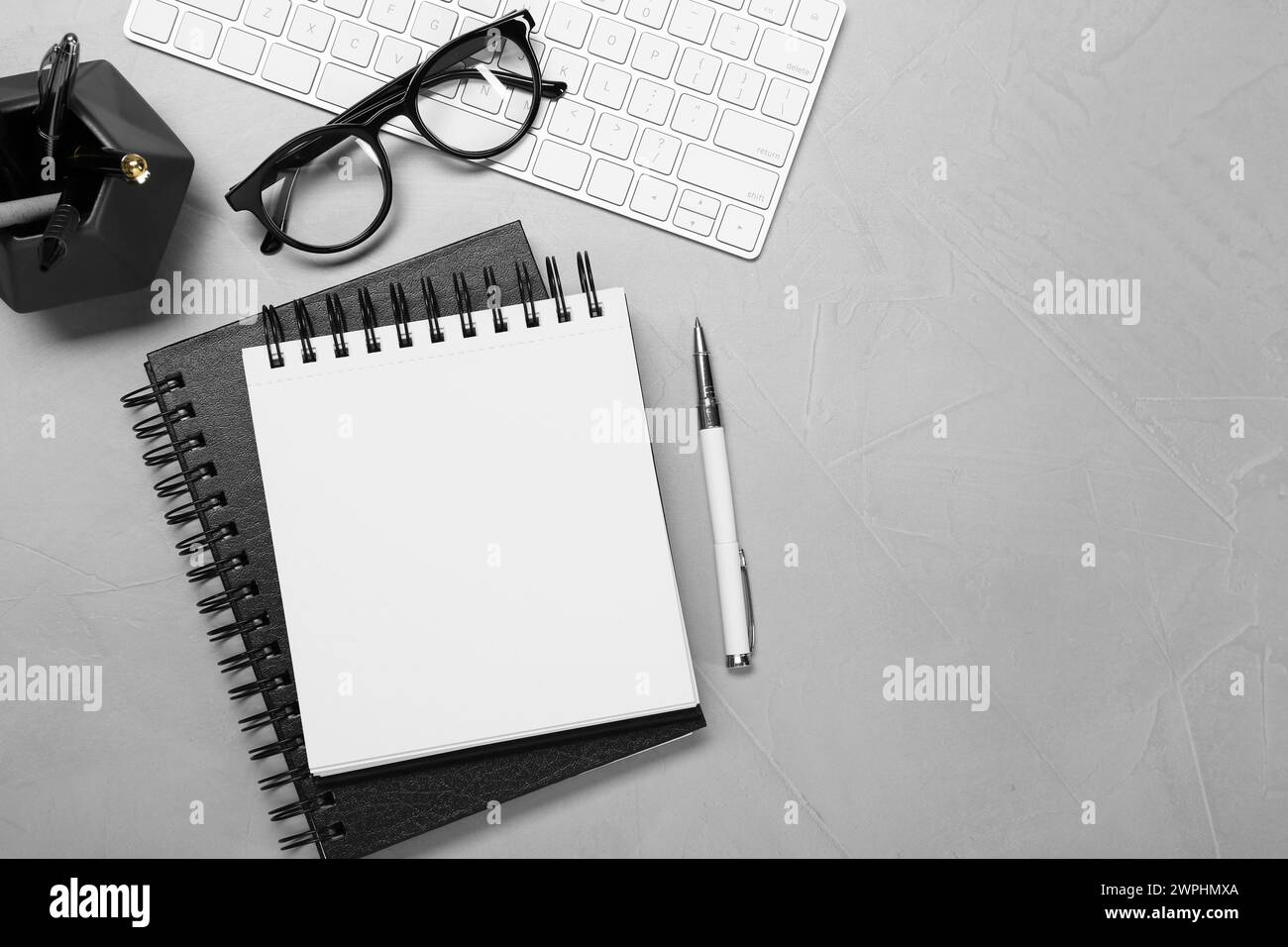 Flat lay composition with notebooks, keyboard and glasses on light grey table Stock Photo