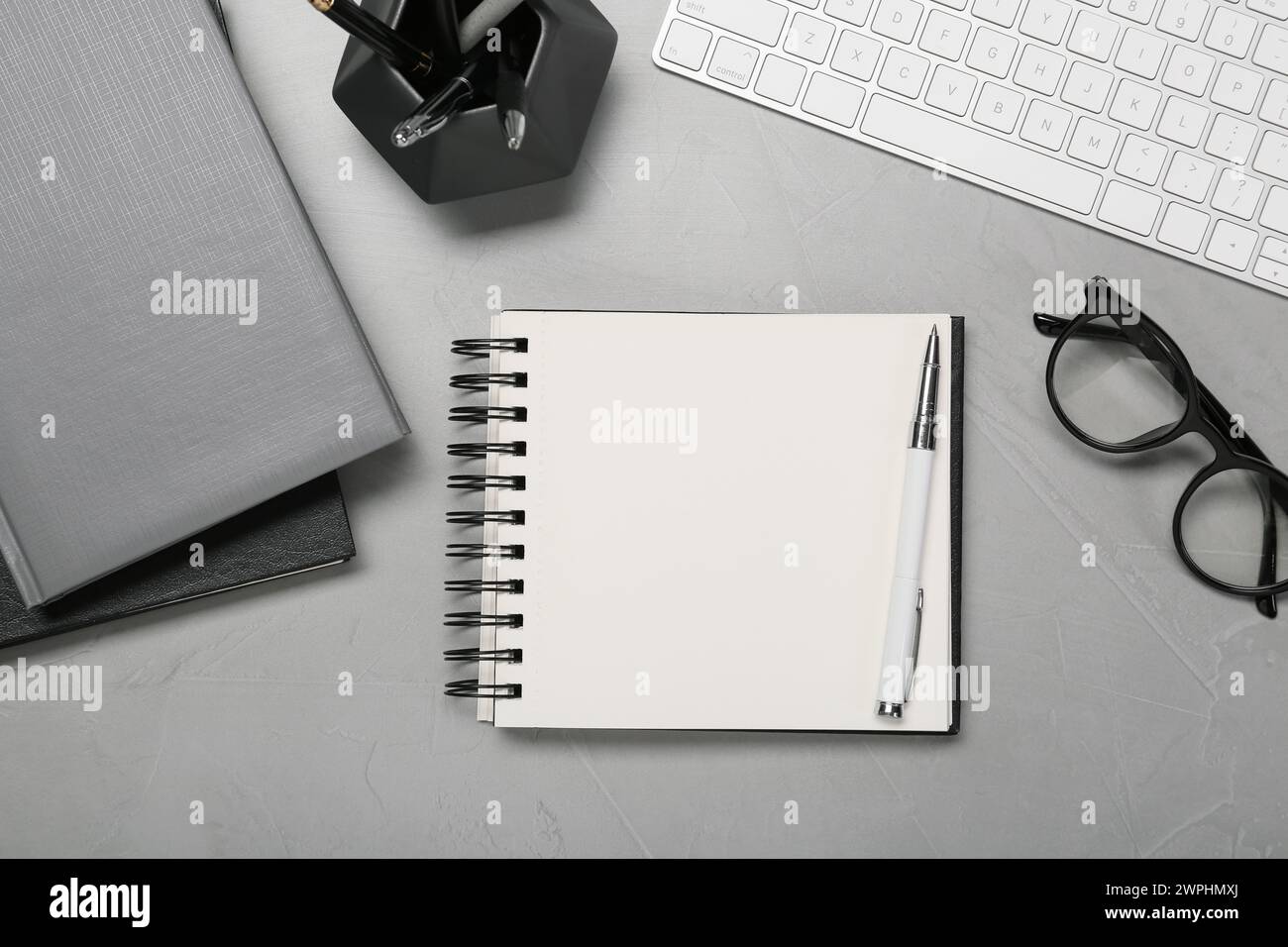 Flat lay composition with notebooks, keyboard and glasses on light grey table Stock Photo