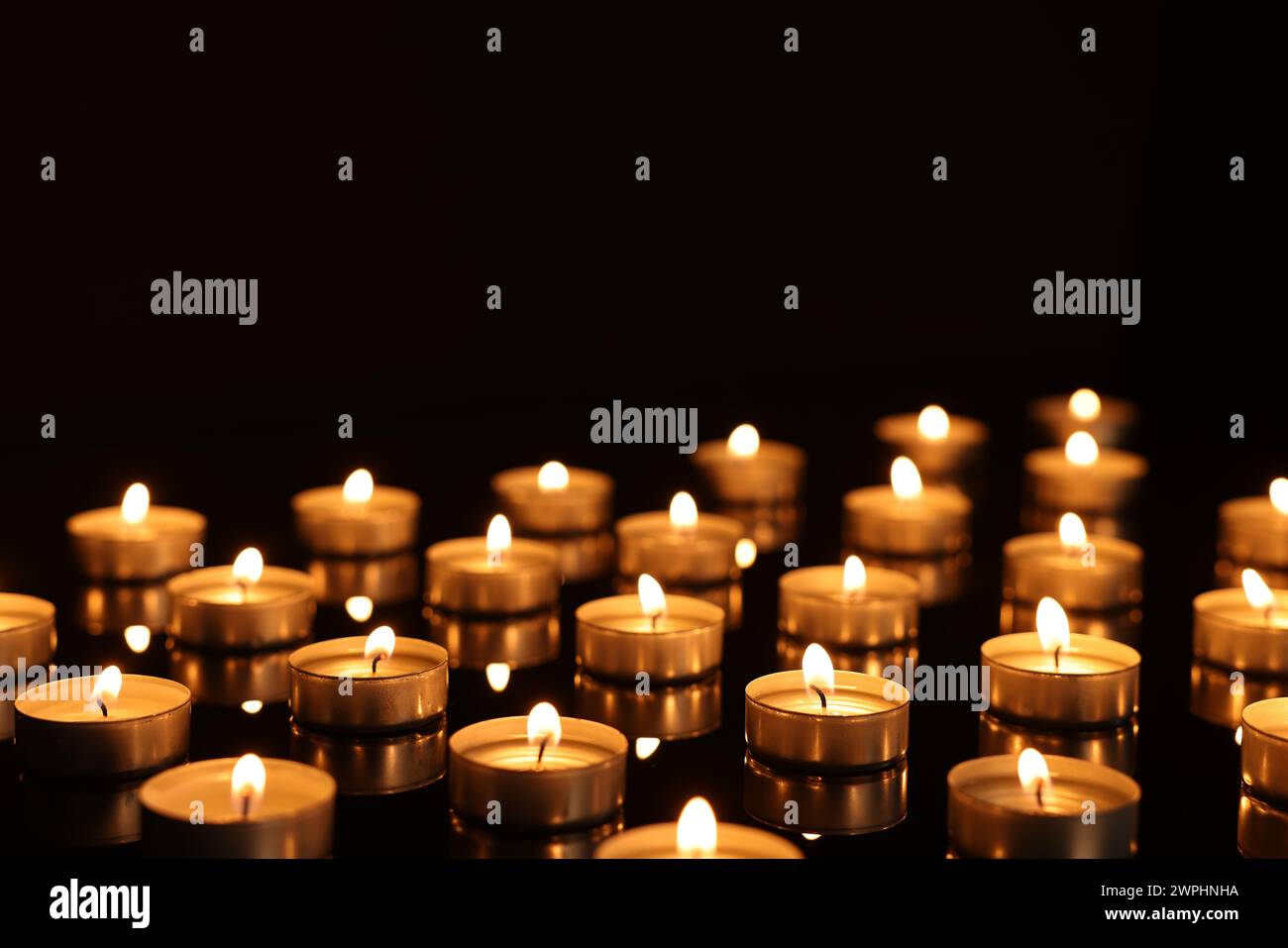 Burning candles on mirror surface in darkness Stock Photo - Alamy