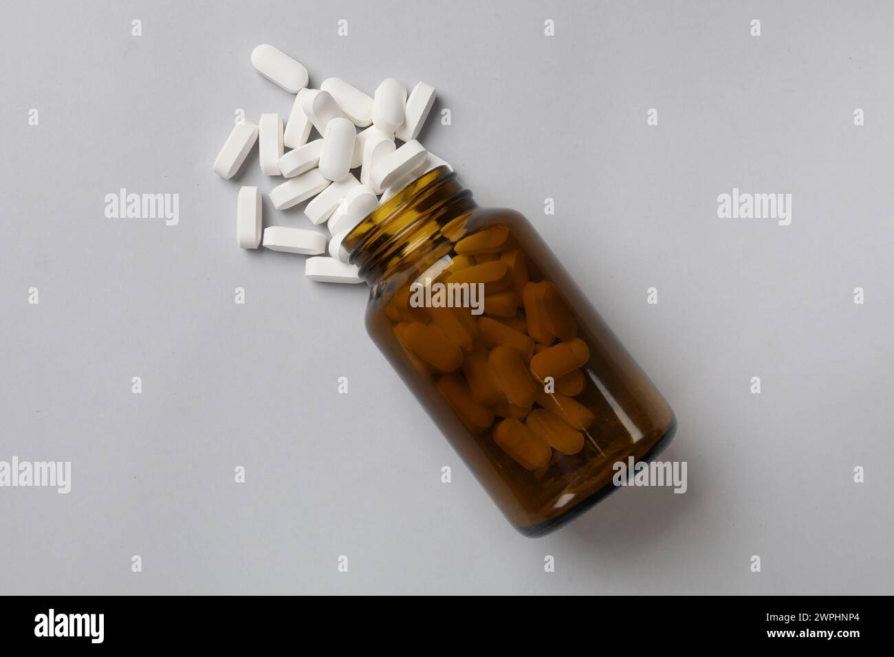 Vitamin pills and bottle on light grey background, top view Stock Photo