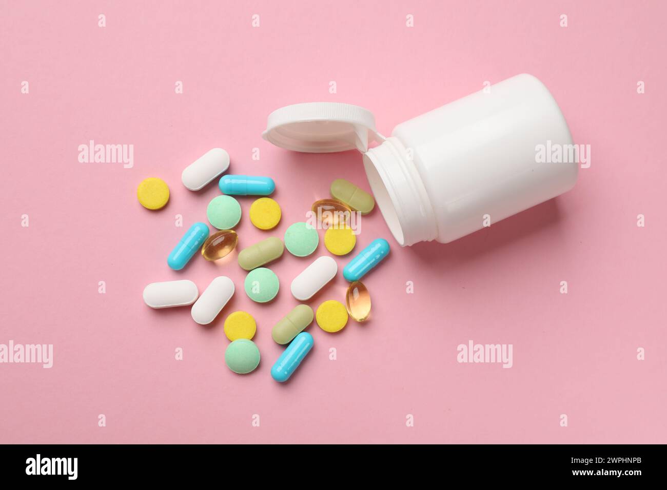 White bottle and different vitamin pills on pink background, top view Stock Photo
