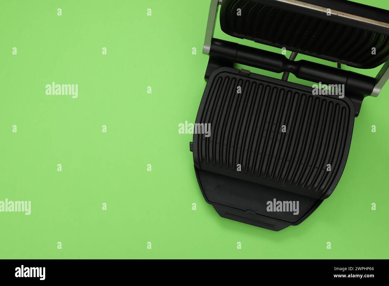 Electric grill on green background, top view. Space for text. Cooking appliance Stock Photo