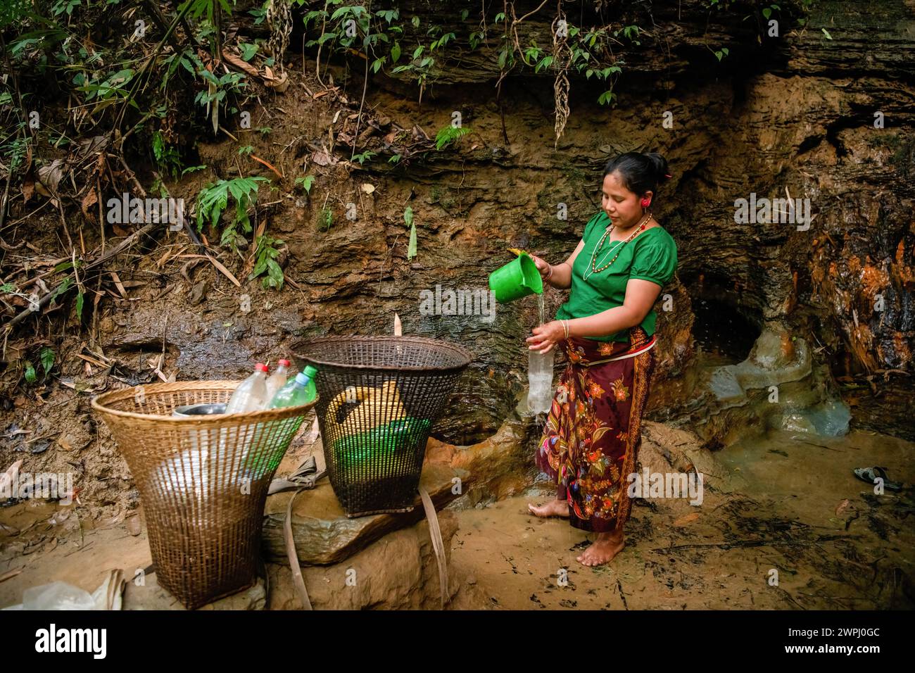 A Mro woman fetches drinking water from a mountain spring. Mro people are an indigenous ethnic group in Bangladesh. They primarily inhabit the Chittagong Hill Tracts (CHT) region, which includes districts such as Bandarban, Rangamati, and Khagrachari. The Mro people are one of the many indigenous communities in Bangladesh, and they have a distinct cultural identity, language, and traditional way of life. Stock Photo