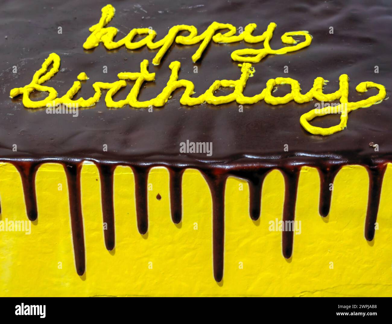 Dark chocolate delight. Happy birthday cake with yellow lettering Stock