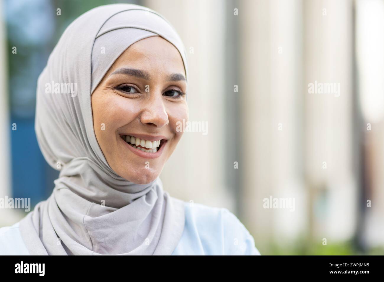 Portrait of a cheerful Muslim woman wearing a hijab outdoors, representing cultural diversity and happiness. Stock Photo