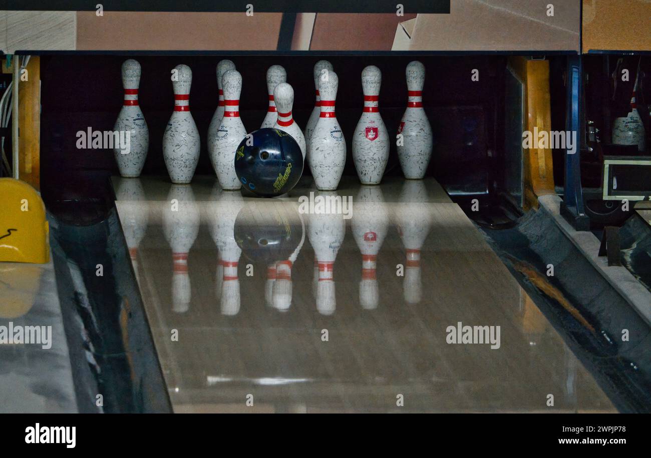 Bowling ball striking and knocking down white pins in the alley. Motion