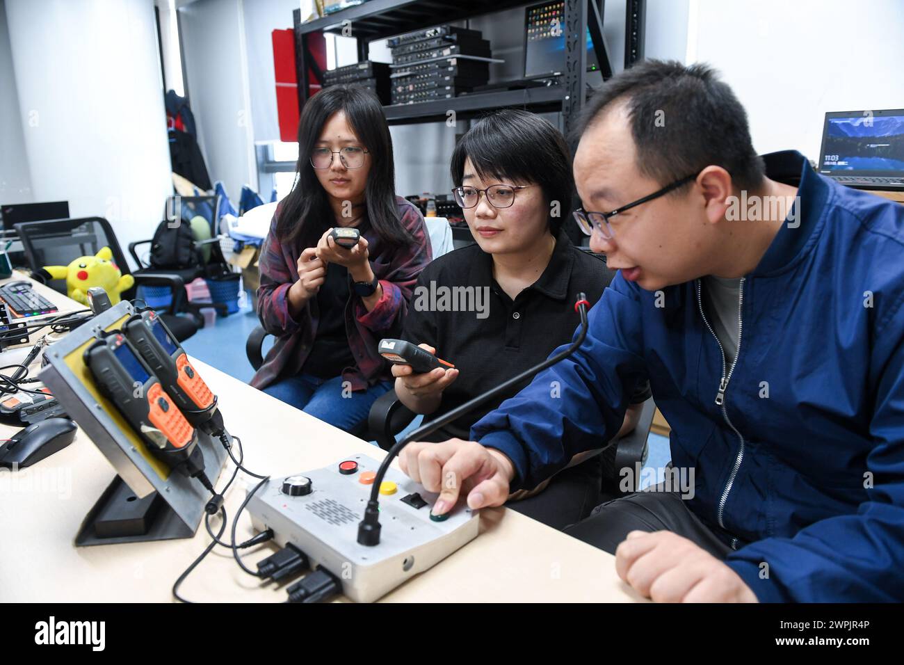(240308) -- SHENZHEN, March 8, 2024 (Xinhua) -- Chen Shuxian (C) tests equipment with colleagues at an office in Shenzhen, south China's Guangdong Province, Feb. 20, 2024. Chen Shuxian is a technical director of the wireless software test group of Shenzhen SED Wireless Communication Technology Co., Ltd. Her office is filled with small brick-like handhelds, which are mainly used for wireless communication in rail traffic. 'I feel a sense of fulfillment every time I see the conductors of high-speed trains using the handhelds,' Chen said. After joining the company in 2008, Chen participated i Stock Photo