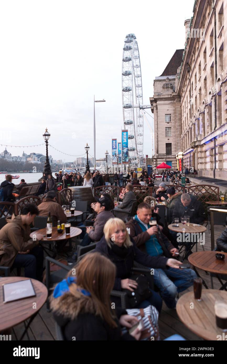 UK, London, People enjoying a drink at the County Hall Arms with the London Eye in the background. Stock Photo