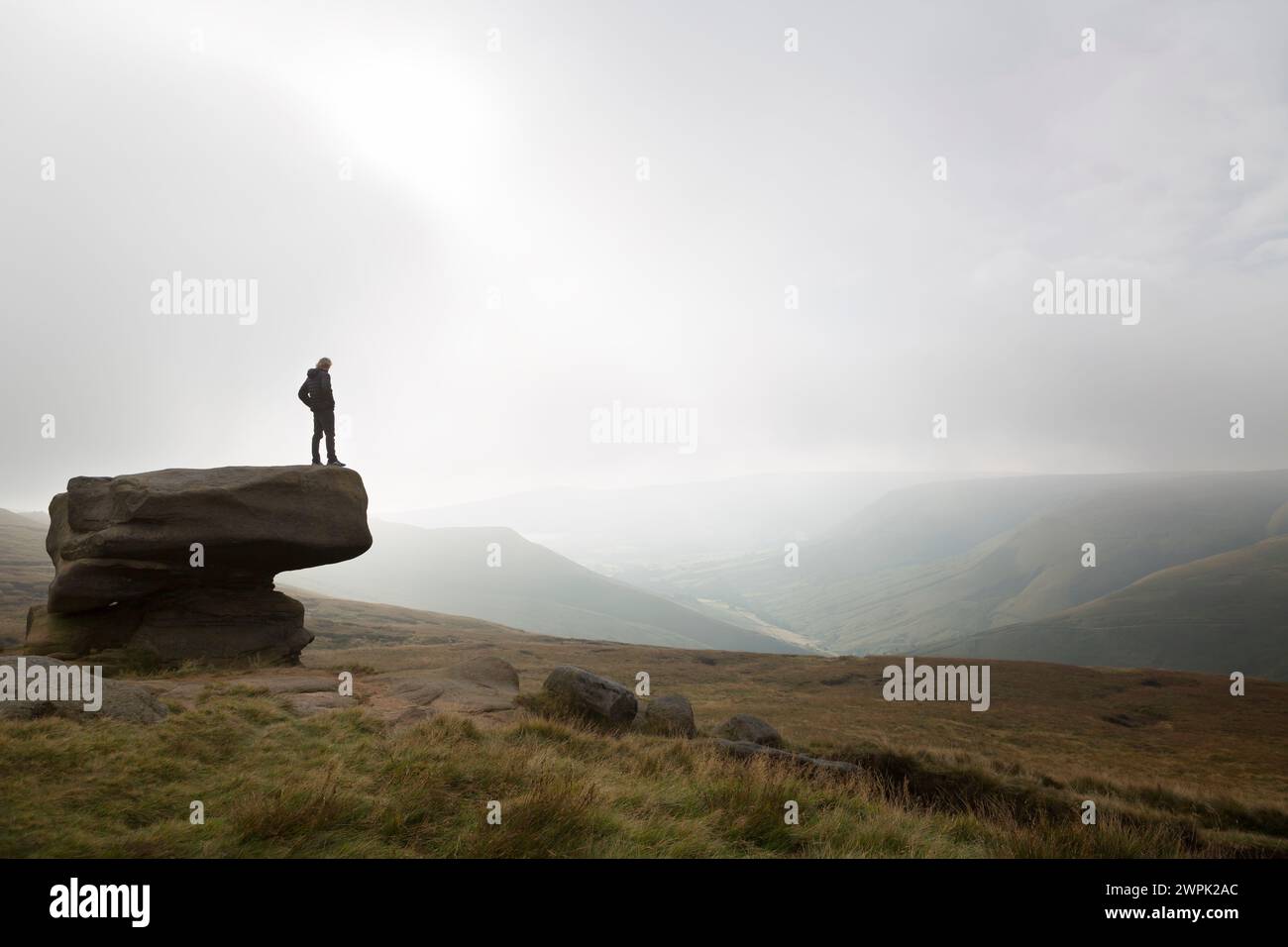 UK, West Yorkshire, view along Kinder Scout skyline with figure on balanced rock. Stock Photo