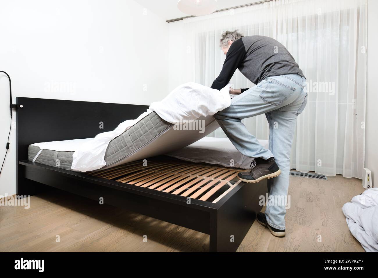 Older man working in bedroom on making bed Stock Photo