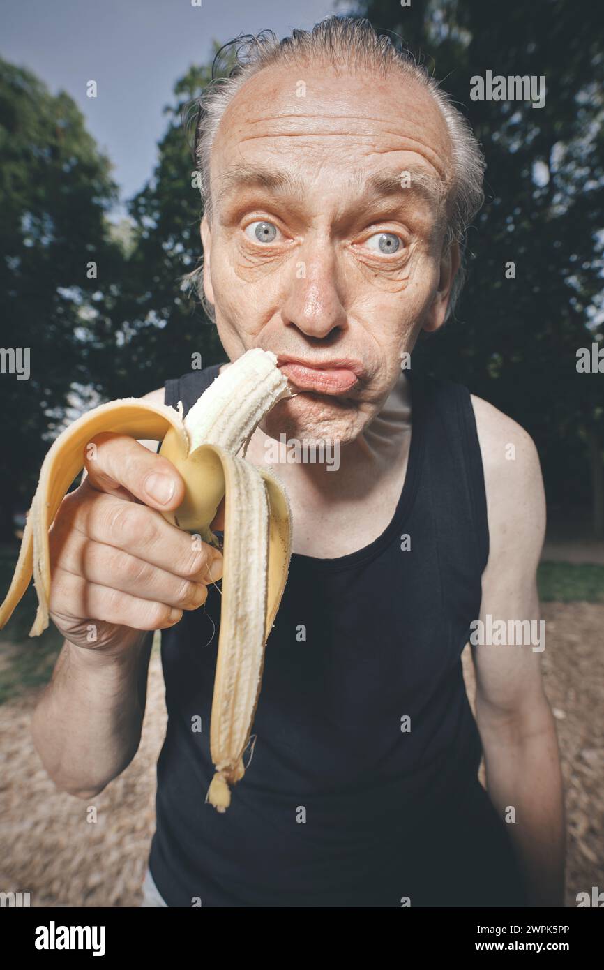 Ugly man of bad condition eating fresh banana after workout Stock Photo
