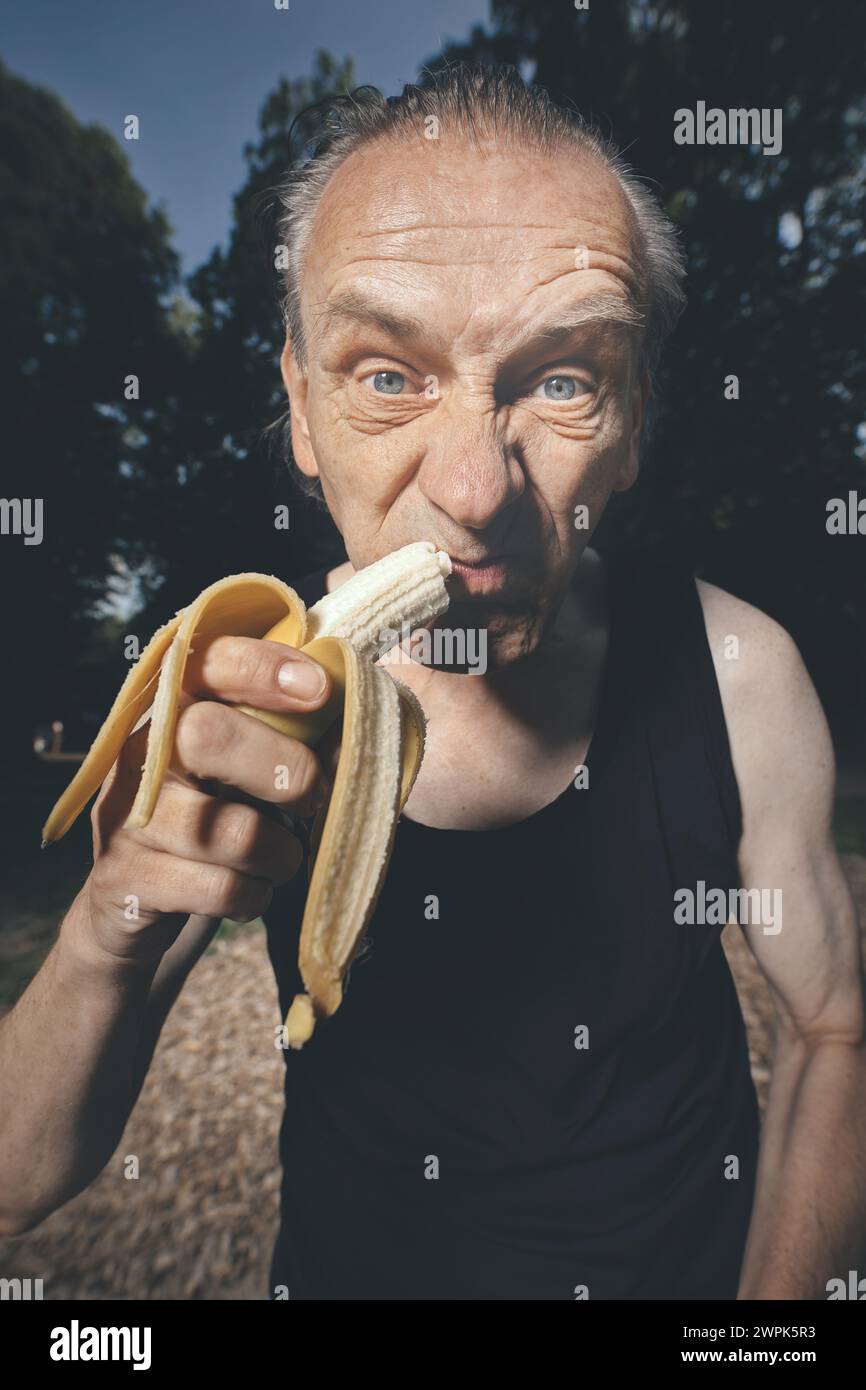 Ugly man of bad condition eating fresh banana after workout Stock Photo