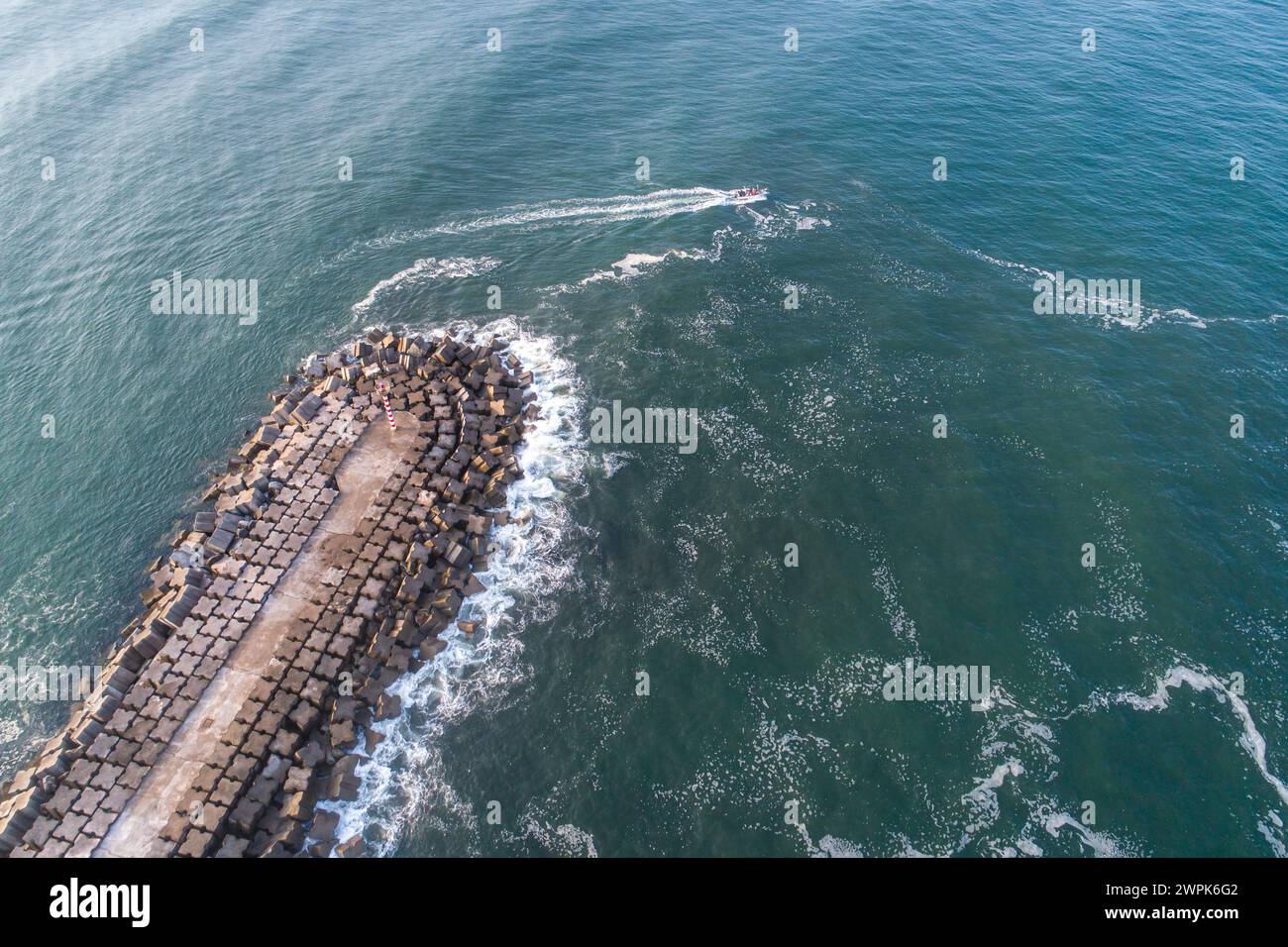 drone aerial view of a breakwater and a fishing vessel at sea Stock Photo
