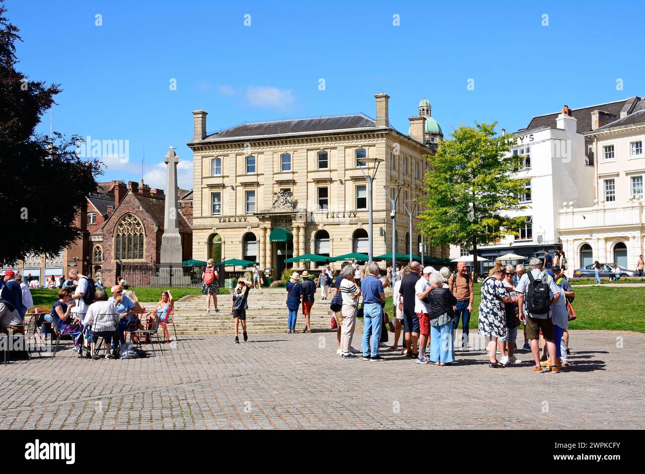 View of The Ivy Bistro and St Pentrock church along Cathedral Yard with tourists in the foreground, Exeter, Devon, UK, Europe. Stock Photo