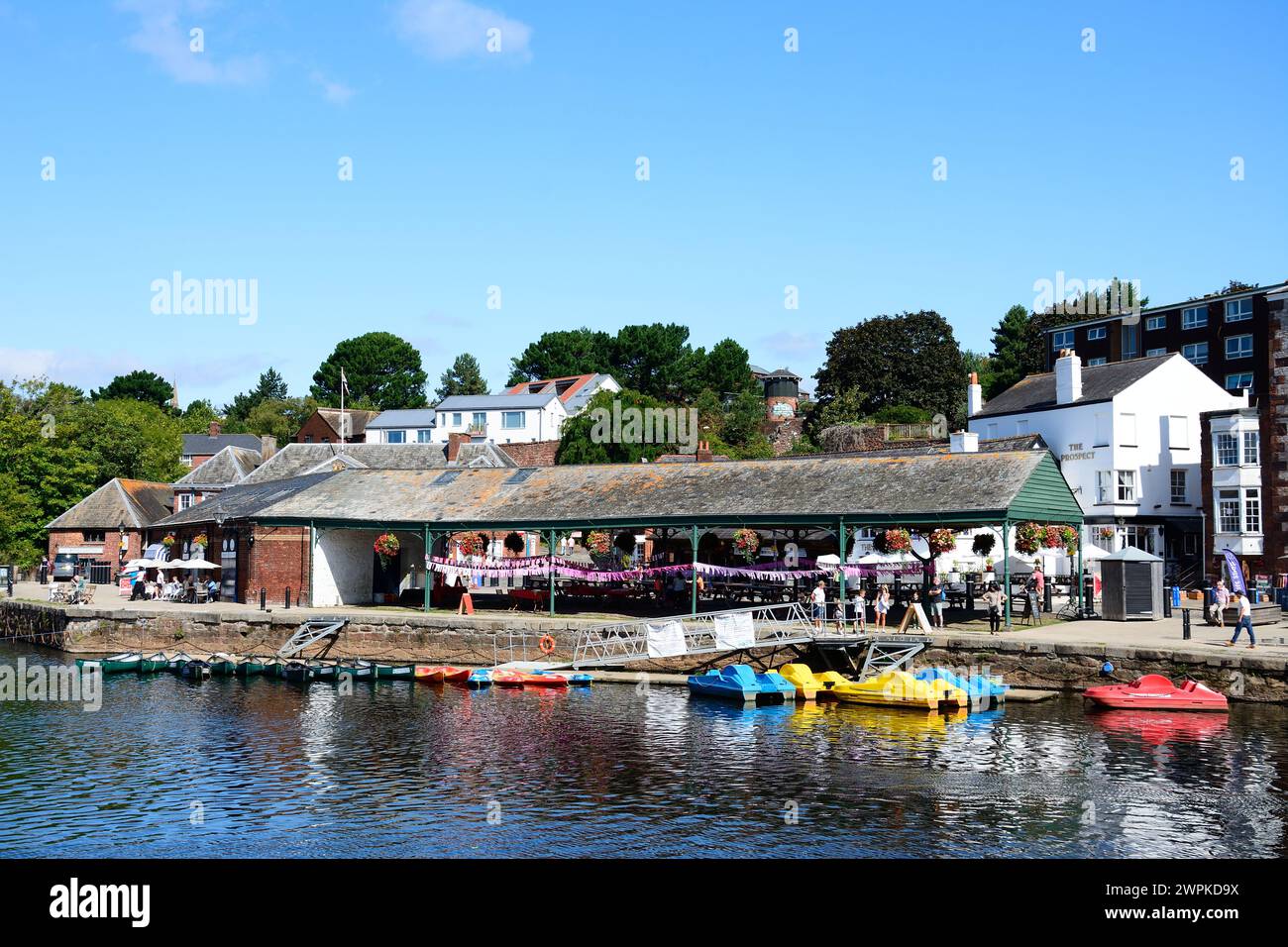 Rowing boats and pedalos moored on the River Exe with shops and restaurants along the East Quay to the rear, Exeter, Devon, UK, Europe. Stock Photo