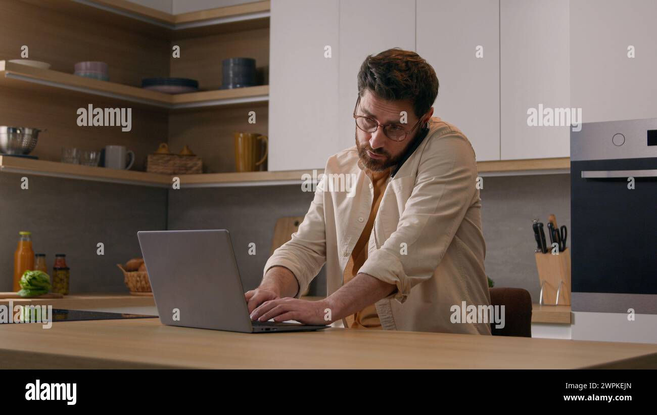 Caucasian multitasking man with laptop working from home talking mobile phone business freelancer businessman at quarantine. Male client order food Stock Photo