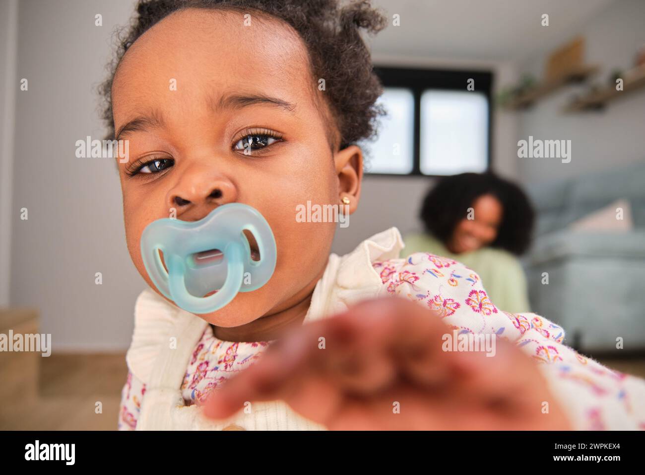 Cuban toddler baby girl trying to reach the camera at home. Stock Photo