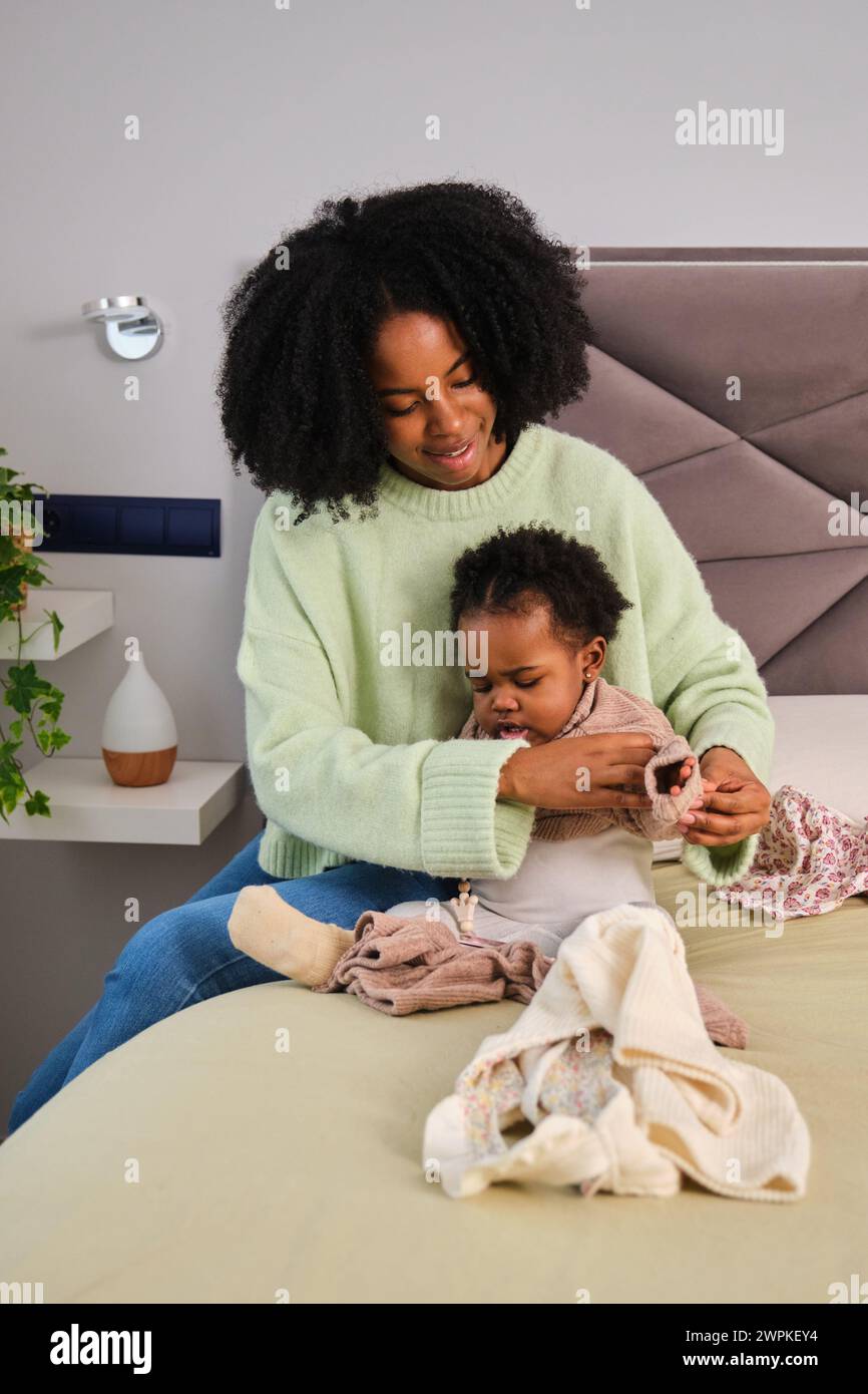 Cuban mother put on pajamas to her toddler daughter on bed Stock Photo ...