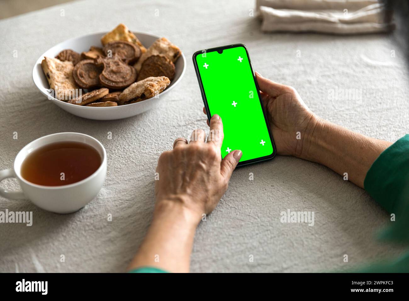 mobile phone with green screen chromakey display in elderly woman hand Stock Photo
