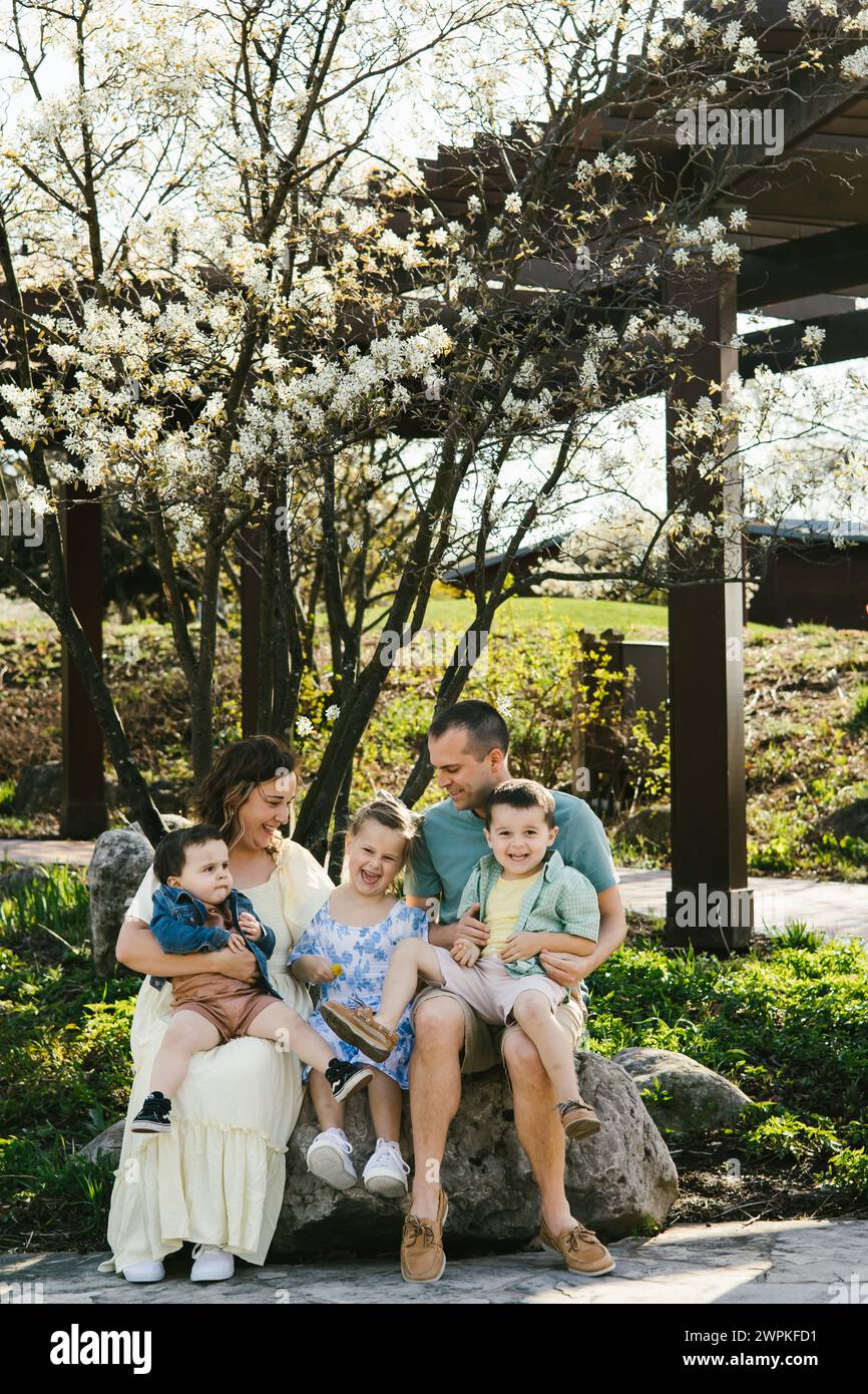 Family laughing together under spring bloom tree in garden Stock Photo