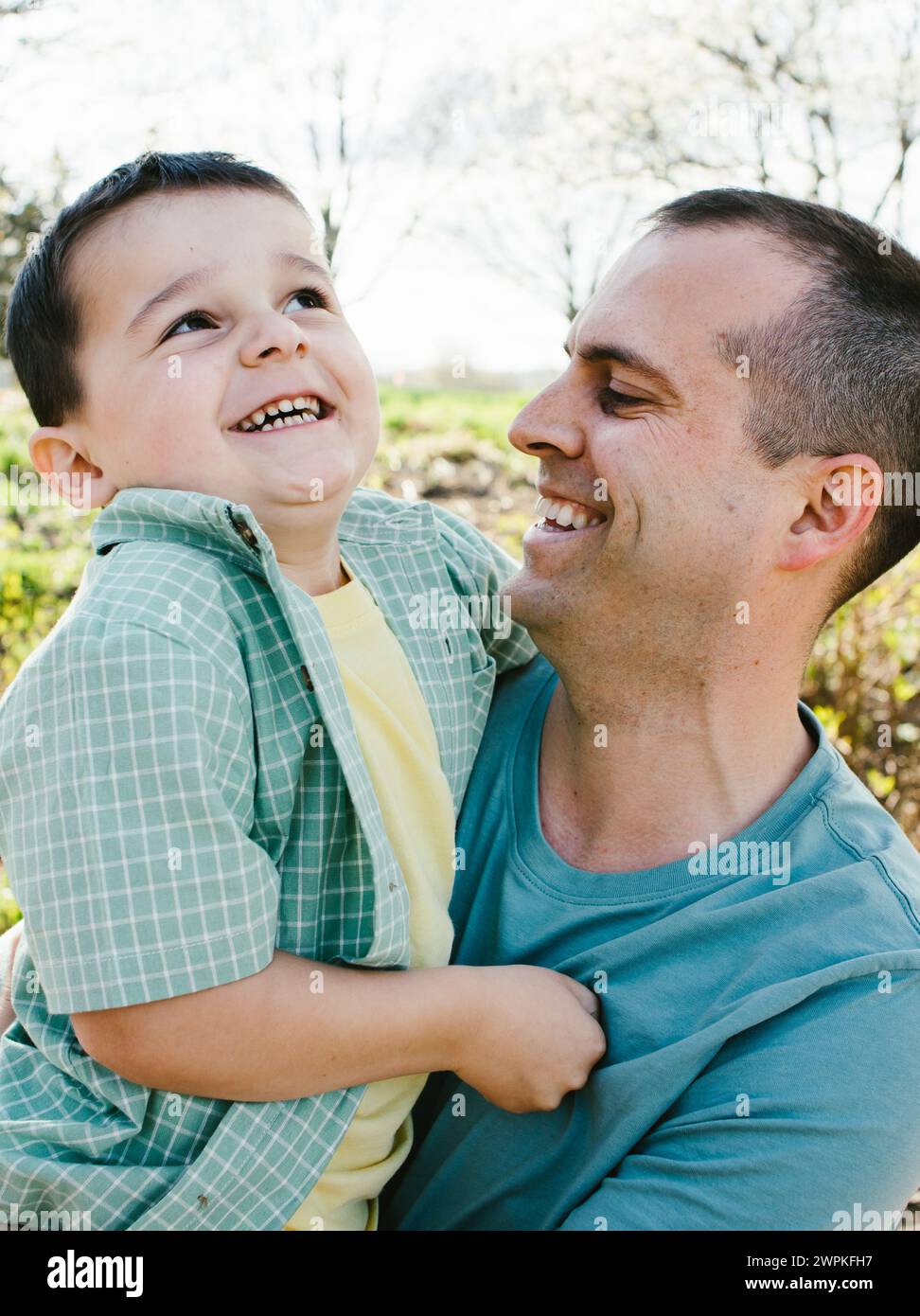 Laughing and smiling father holding son together in spring Stock Photo