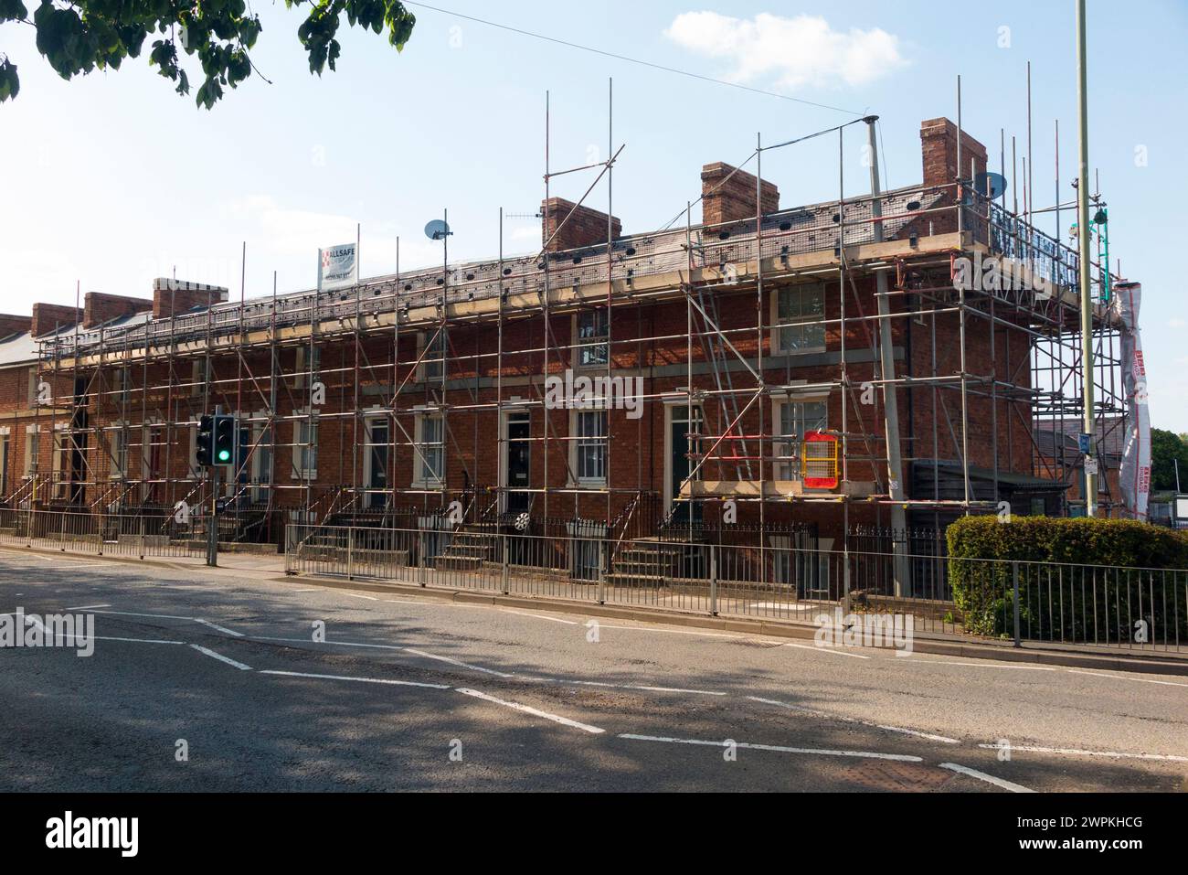 Scaffolding around a long row of identical Victorian terraced houses which are having a new roof, including end of terrace house. Banbury. UK. (134) Stock Photo