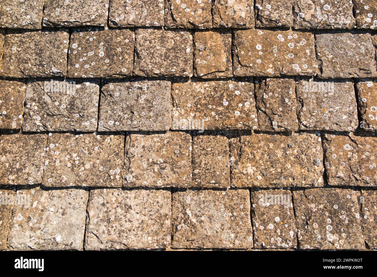 A stone roof made with / covered with tile stones of sedimentary limestone rock, on a house in the Cotswolds, Oxfordshire. Stock Photo