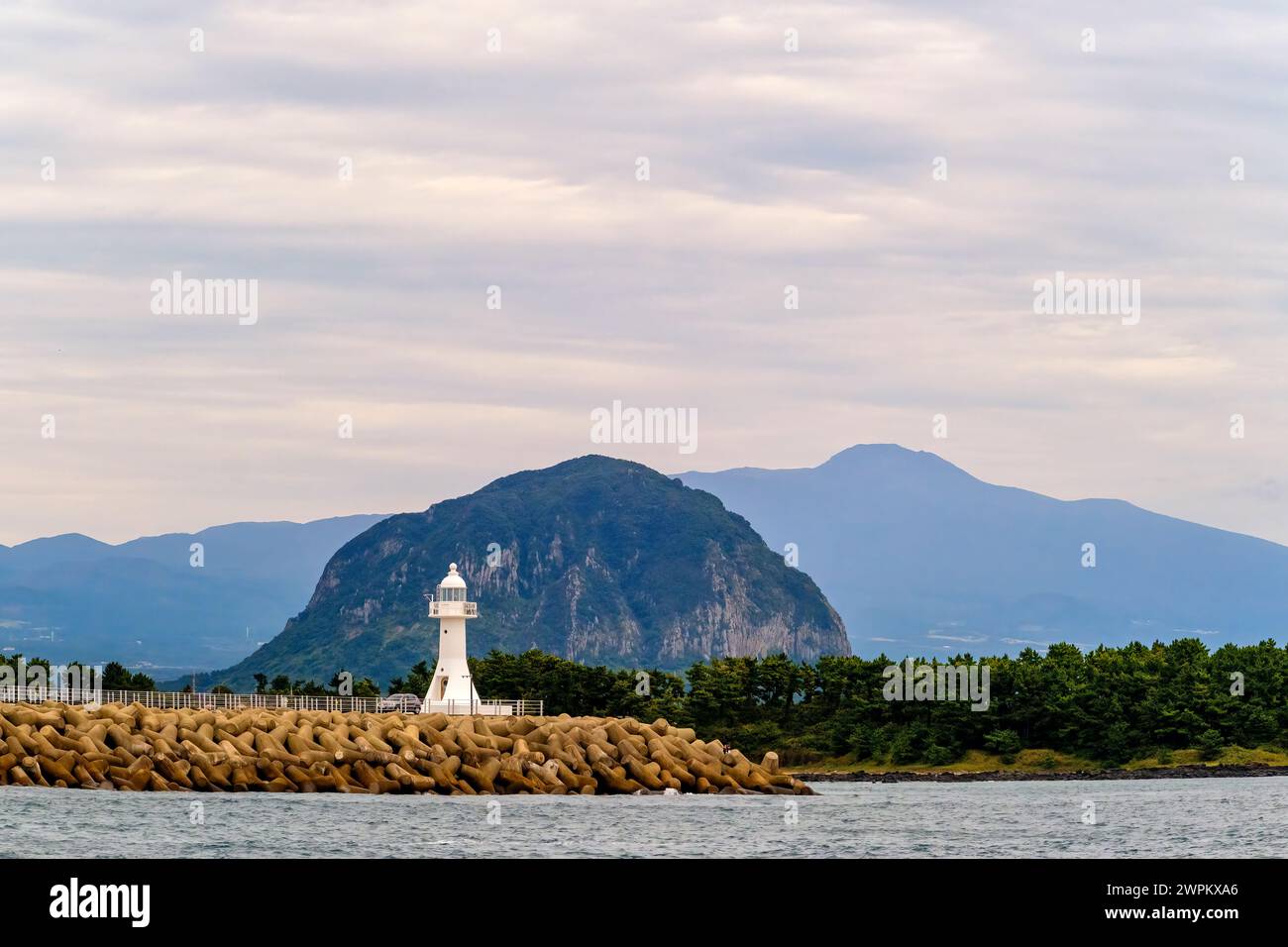 One of Jeju Island's many lighthouses stands against Mount Sanbangsan and Mount Hallasan, a shield volcano, Jeju Island, South Korea, Asia Stock Photo