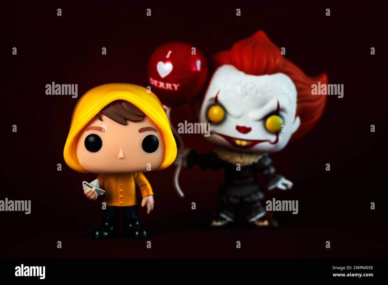 Funko POP vinyl figures of Pennywise with balloon and Georgie characters of the movies and the book It over dark background. Illustrative editorial Stock Photo