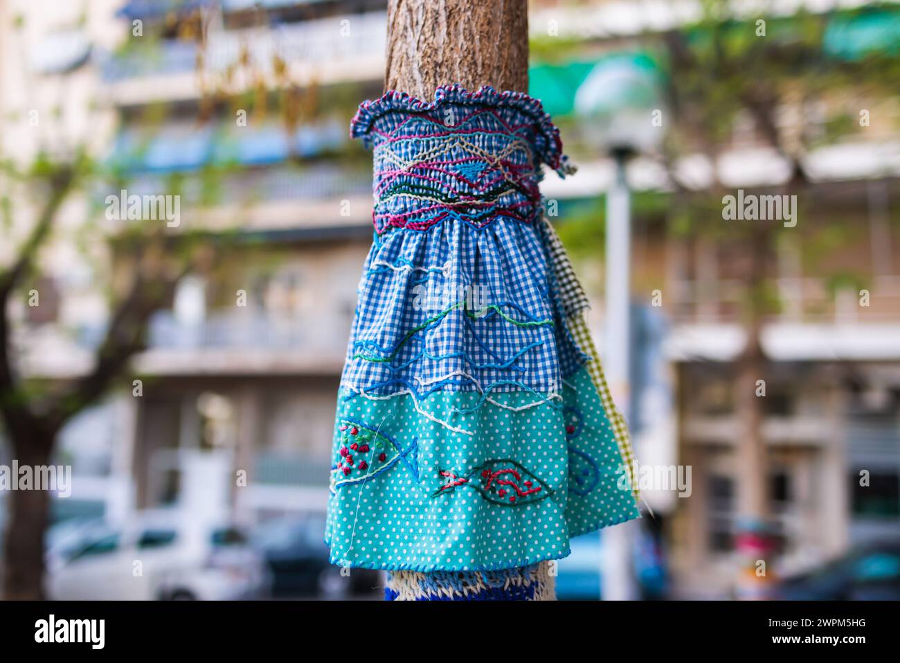 Yarnbombing, trees decorated with yarn bombing, knitted graffiti street art, kniffiti in the european city, colored urban knitting, process of graffit Stock Photo