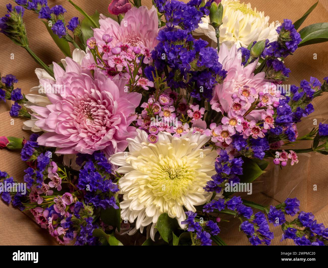 Bird's eye view of a bouquet of pink and purple flowers wrapped in brown paper. Stock Photo