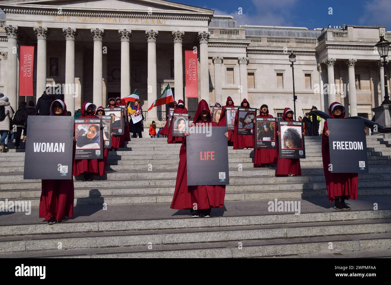 London, UK. 8th March 2024. Protesters stand in Trafalgar Square with pictures of the victims of the Iranian regime. Women wearing The Handmaid's Tale costumes marched through central London in support of freedom for Iran on International Women's Day. Credit: Vuk Valcic/Alamy Live News Stock Photo