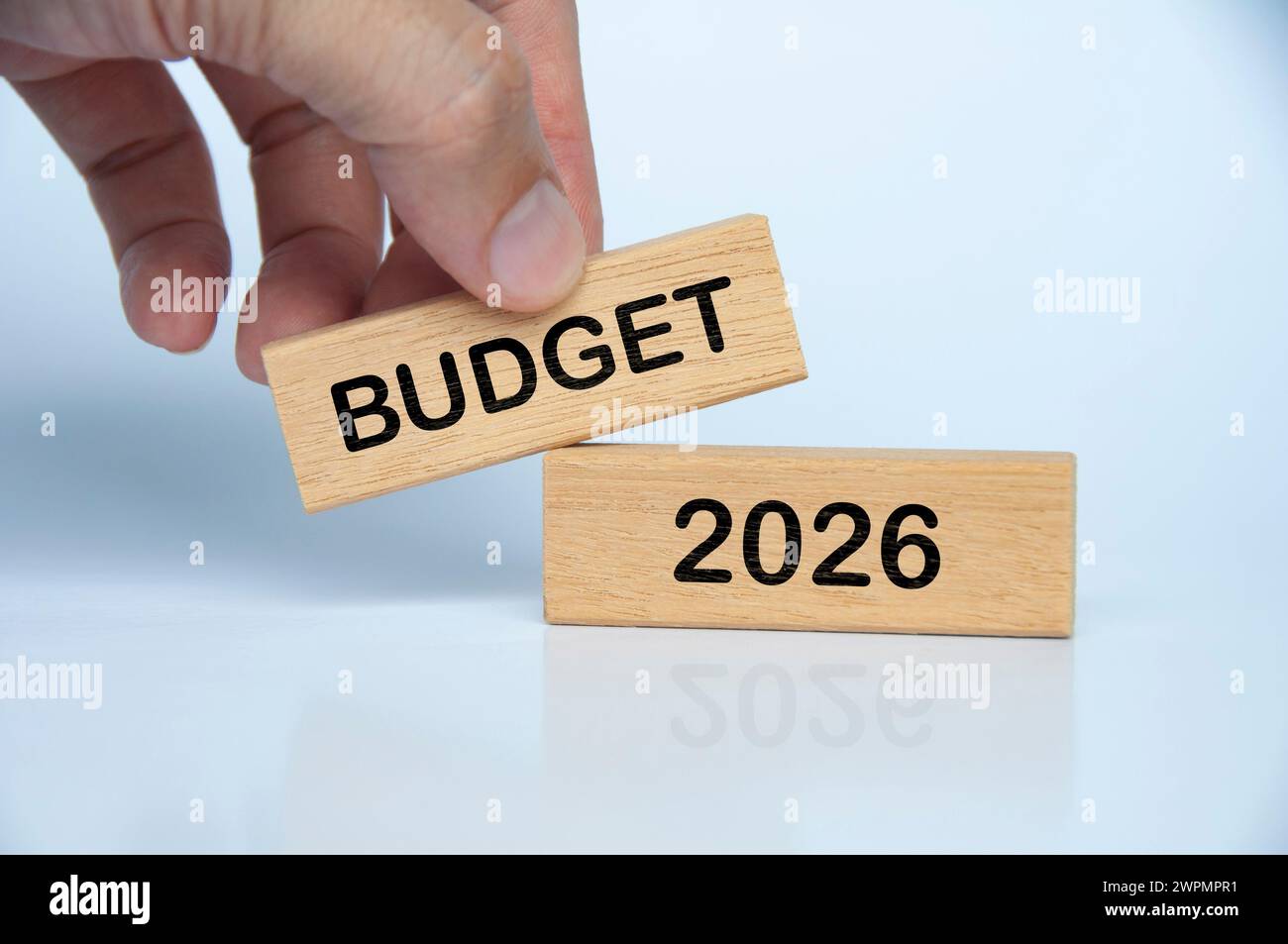 Hand holding wooden block with Budget 2026 text on white background