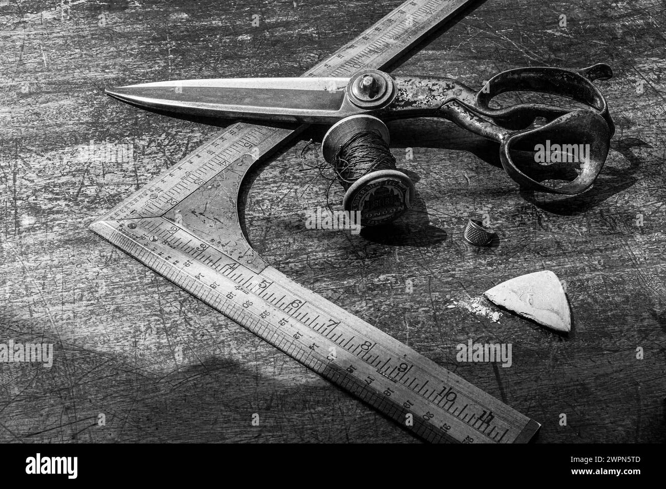Old tailor measuring tool with scissors and chalk on tailors work bench Stock Photo