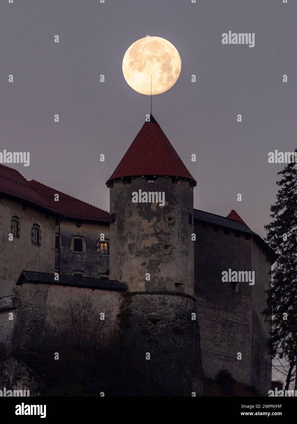 Moonset behind the castle of Bled. Stock Photo