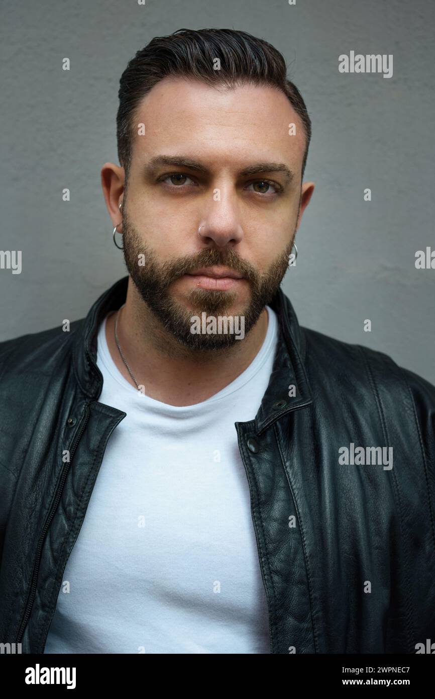 Fashionable man in a sleek leather jacket poses confidently - Embodying edgy urban style with a cool gaze Stock Photo