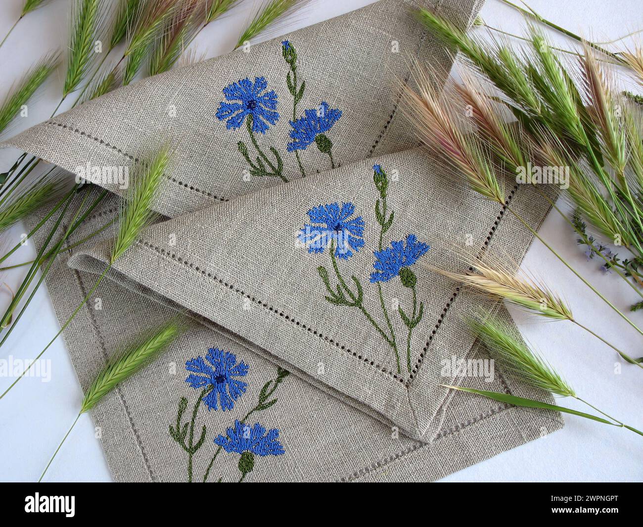 Linen napkins with cornflower embroidery and spikelets, selective focus. Decorated table textile Stock Photo