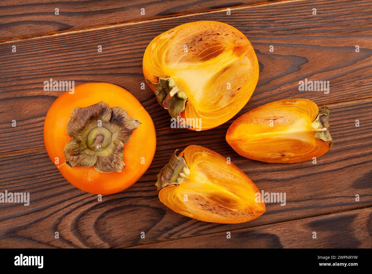 sliced persimmon on wood background top view Stock Photo