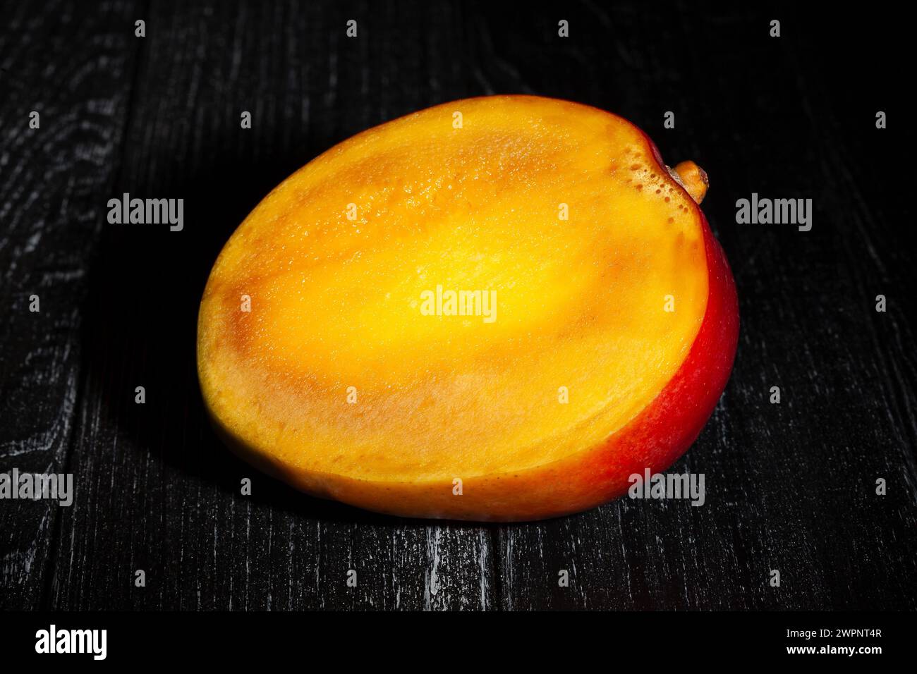 sliced mango on black wood background Stock Photo