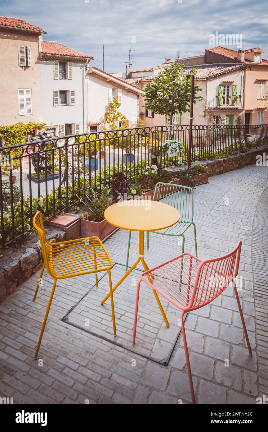 Picturesque old town alley with colorful bistro table and chairs in the medieval town center of Mougins, Provence-Alpes-Cote d'Azur in southern France Stock Photo