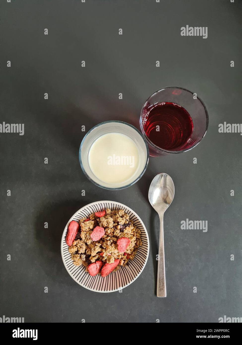 A bowl of grain muesli with strawberries and two glasses of juice and milk to choose from Stock Photo
