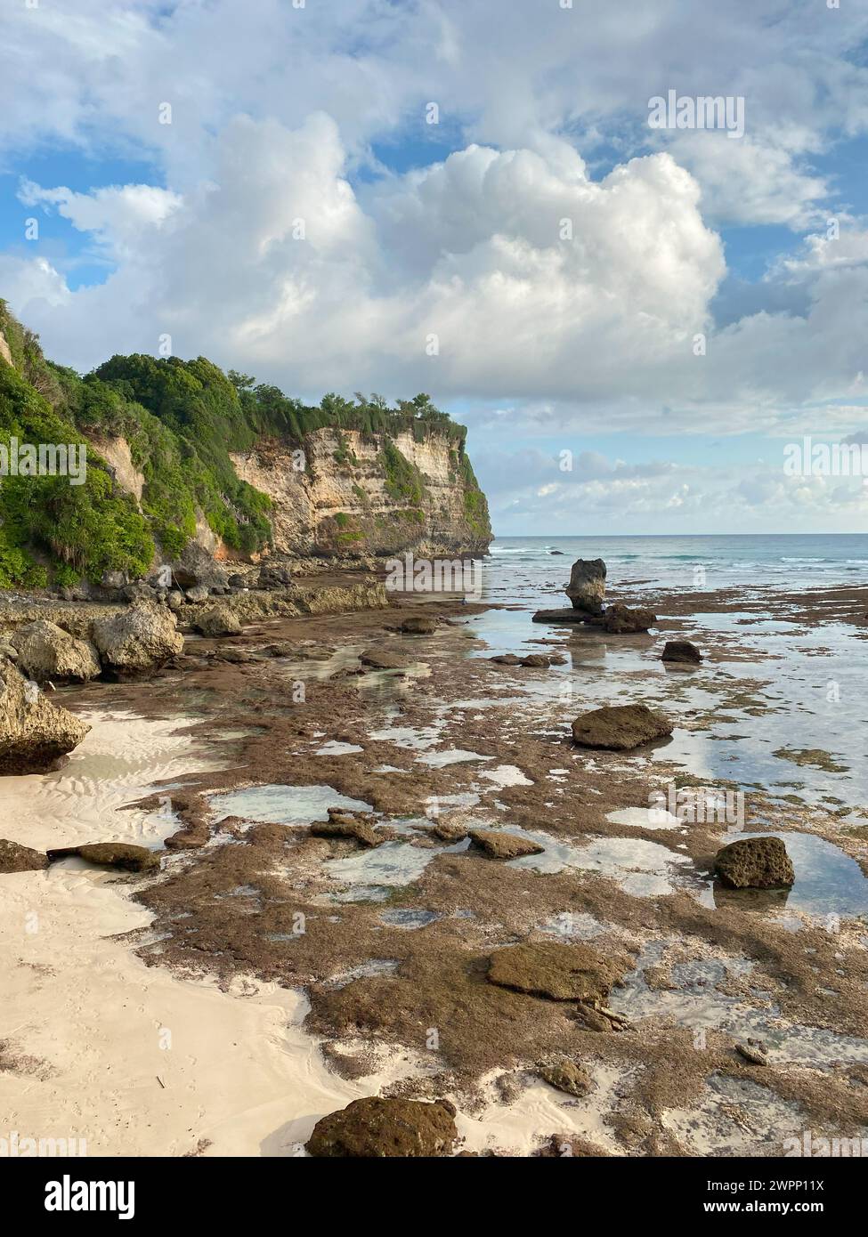 The sheer cliffs of the southern coast of Bali are washed by a clear azure ocean. Bukit Peninsula coastline. Stock Photo